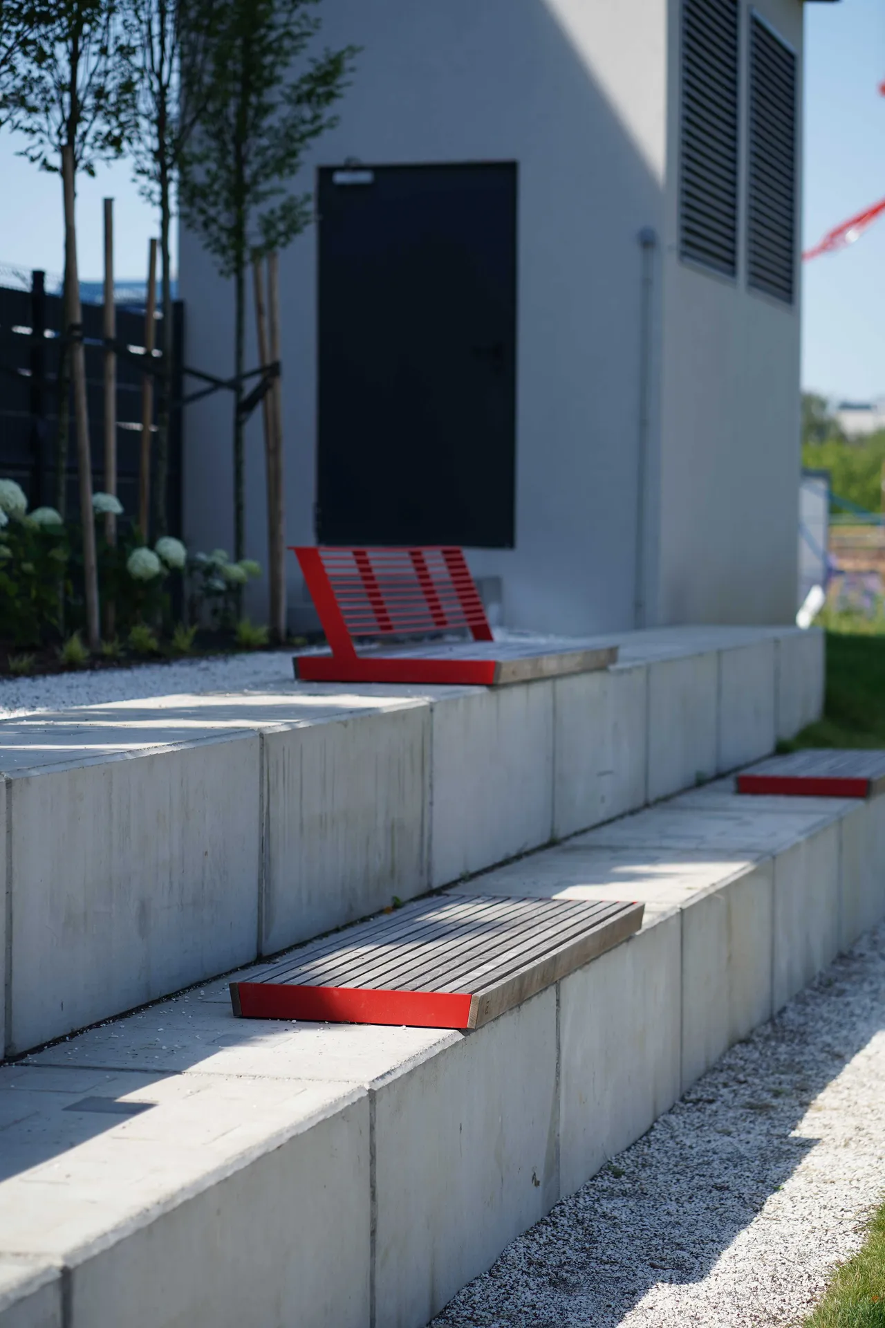Die Abb. zeigt die EGOÉ Bank A1 zur Sockelmontage ohne Rückenlehne, mit Holz aus Thermoesche geölt und Gestell in Verkehrsrot (RAL 3020).