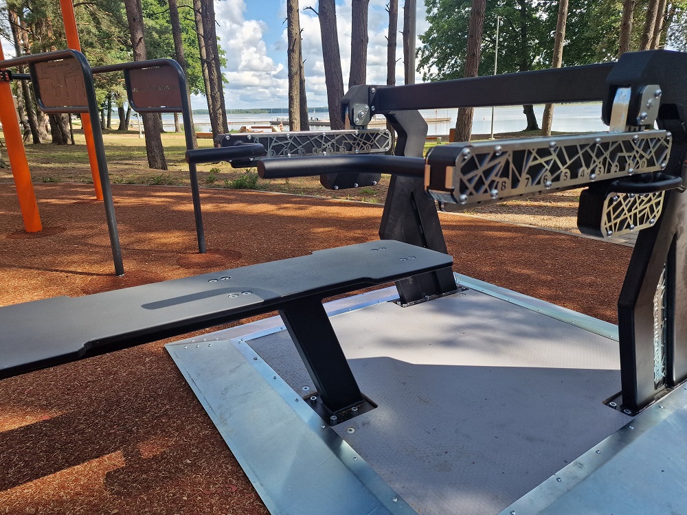 Die Abb. zeigt das Outdoor Kraftgerät Bankdrücken Alpha Steel mit abweichender Bodenplatte.