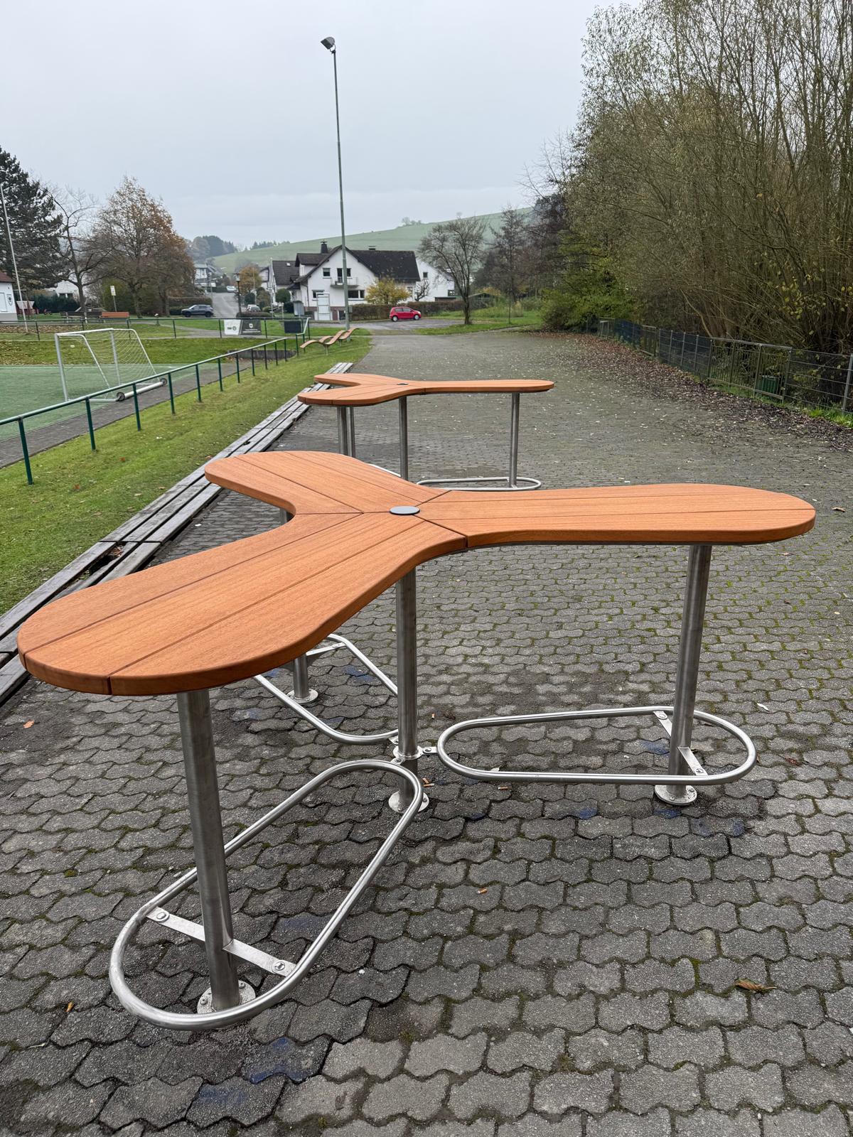 Die Abb. zeigt den Boomerang Stehtisch montiert im Freien (Lieferumfang enthält einen Tisch).