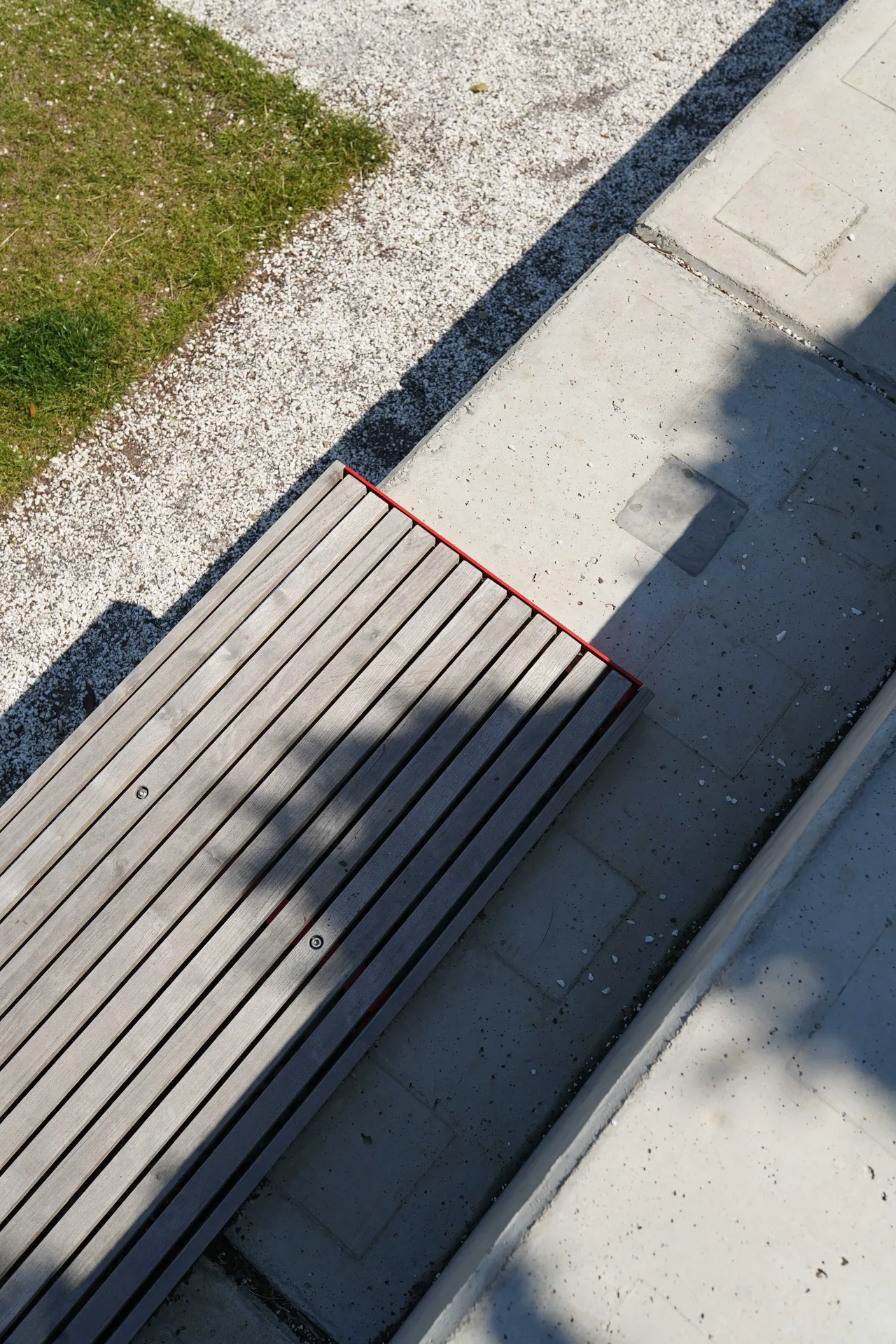Die Abb. zeigt die EGOÉ Bank A1 zur Sockelmontage ohne Rückenlehne, mit Holz aus Thermoesche geölt und Gestell in Verkehrsrot (RAL 3020).